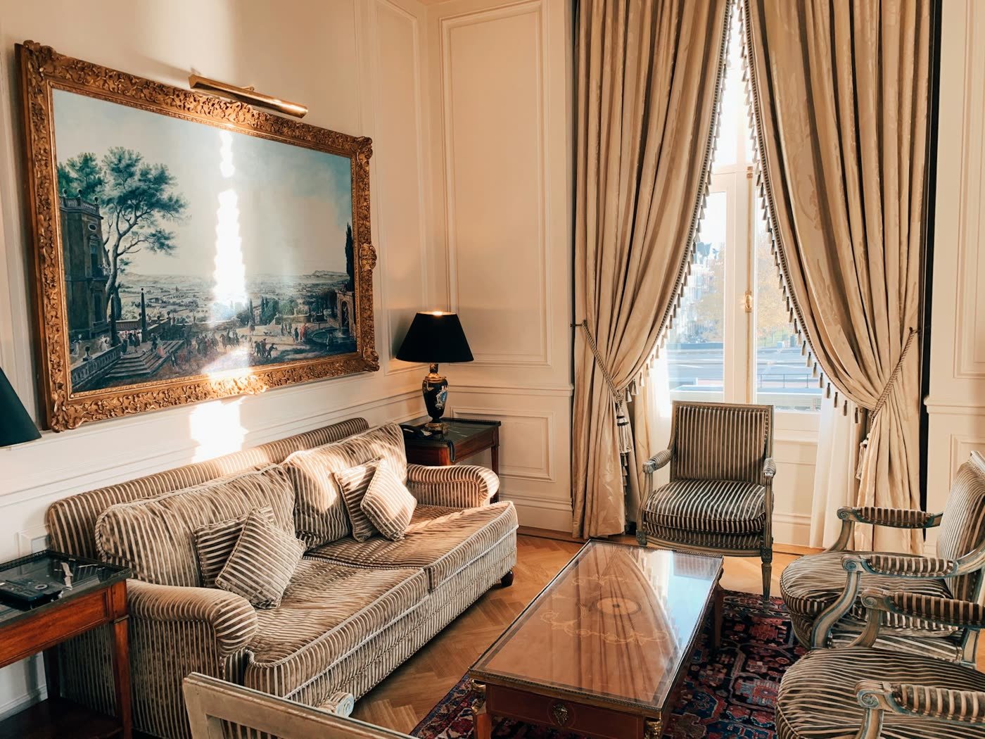 Salón de suite con una obra enmarcada de gran formato sobre el sofá