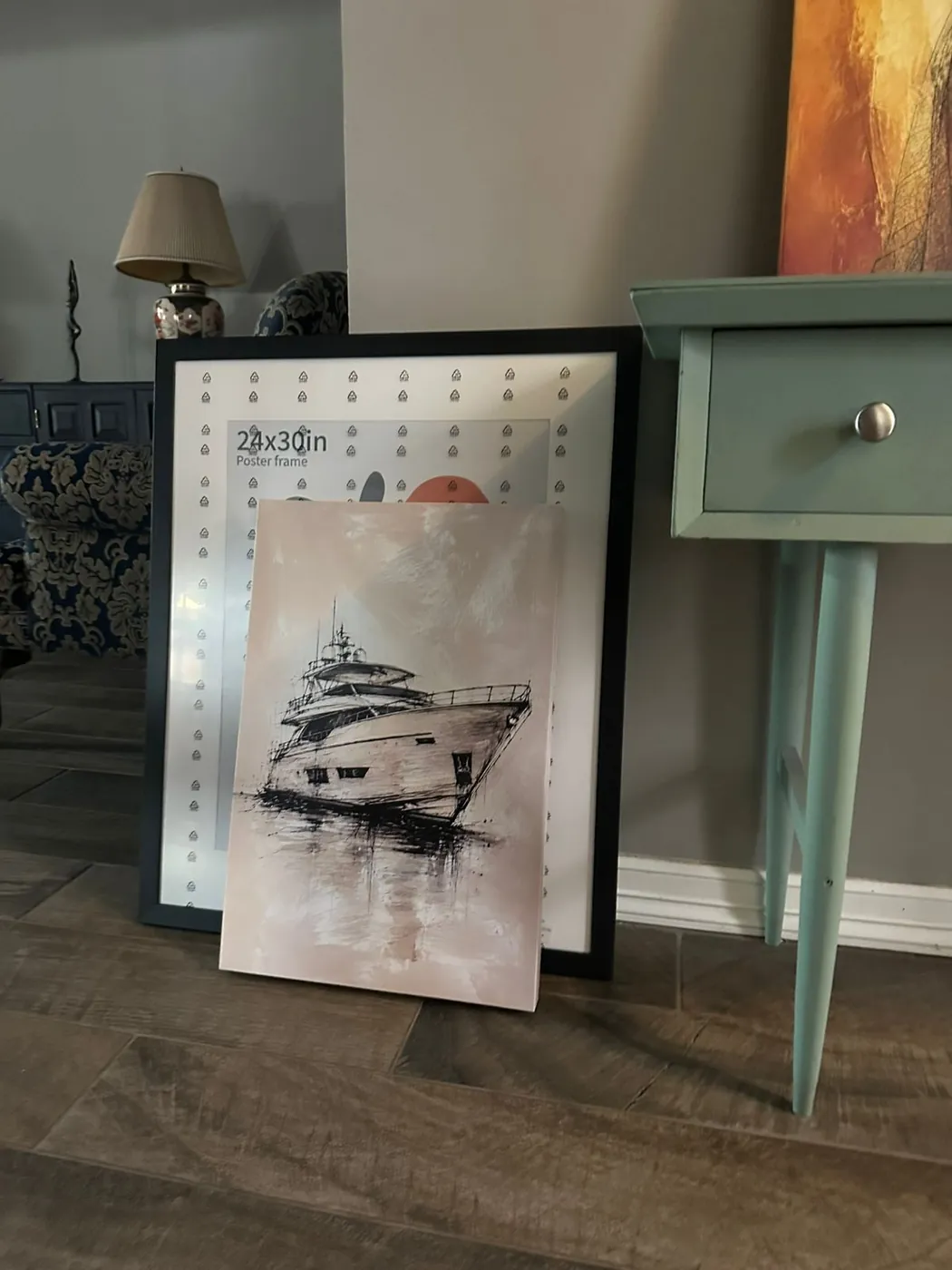 Dos piezas de un yate en tinta, una enmarcada en negro y otra en canvas, apoyadas junto a una consola verde